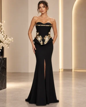 milagros-czarna-sukienka-maxi-z-baskinka-przod Czarna sukienka maxi Milagros z baskinką, złotymi kwiatami i rozcięciem z przodu, na modelce